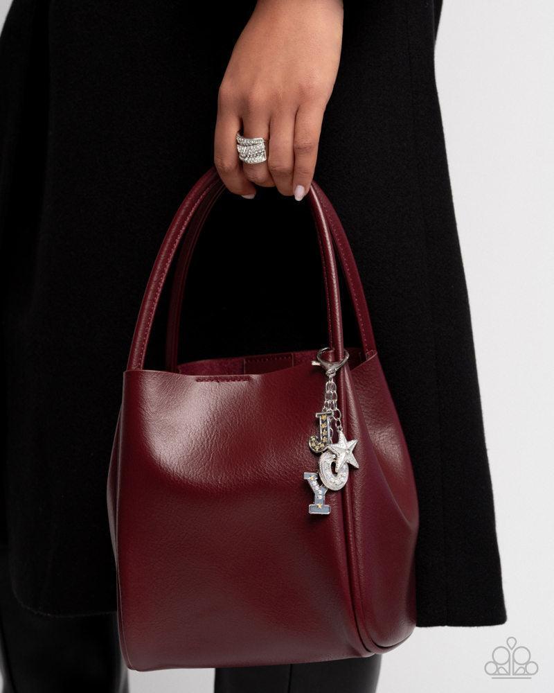 Make a Joyful Noise Multi Silver & White Bag Charm - Paparazzi Accessories- on model - CarasShop.com - Paparazzi Jewelry by Cara Jewels
